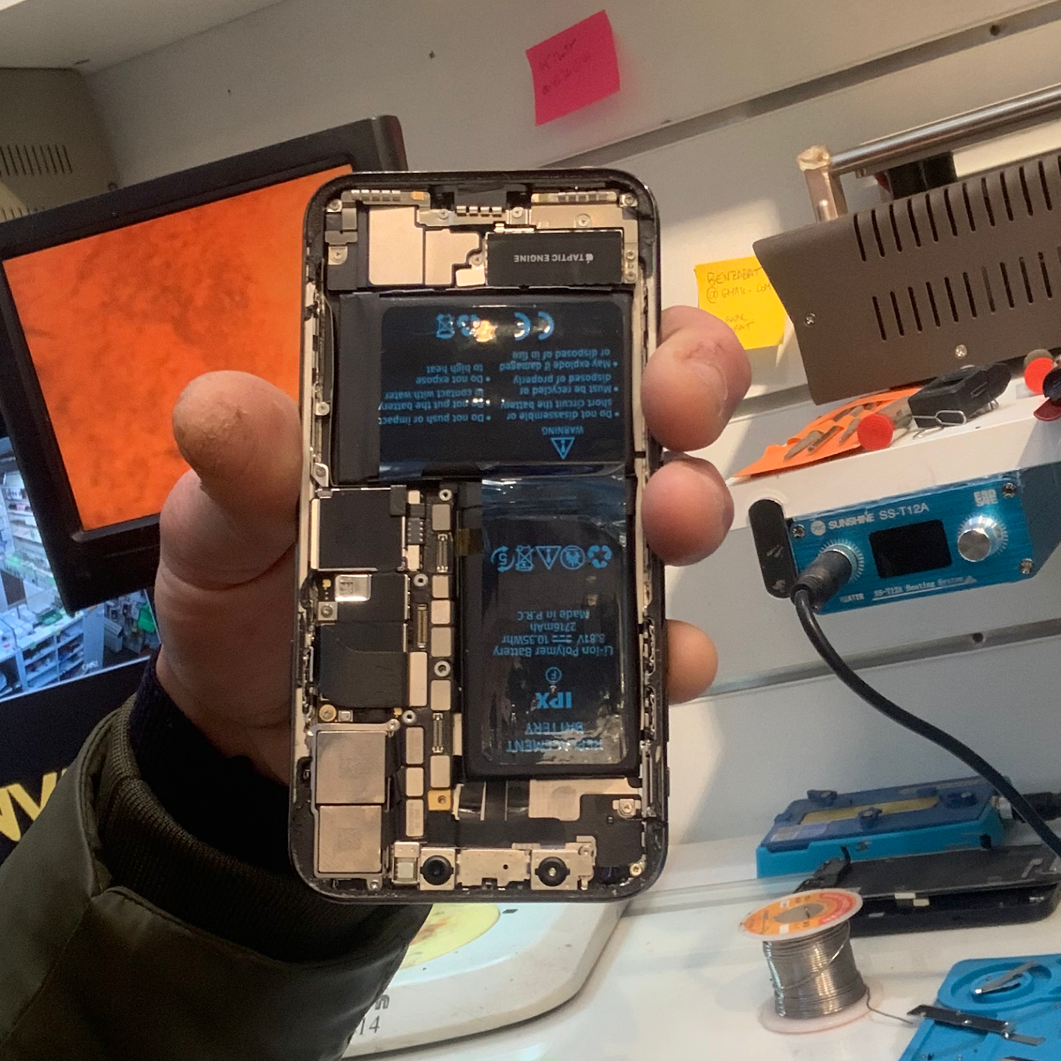 Batterie et composants internes d’un iPhone ouvert à l’atelier SOS PHONE